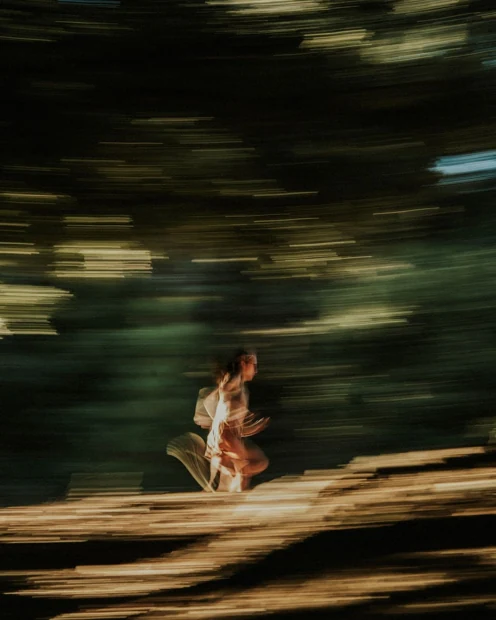 A motion-blurred photograph of a runner in a forest